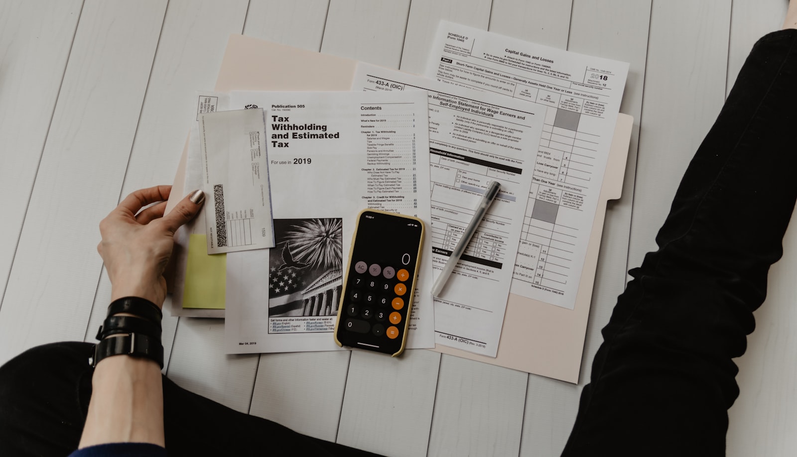 Documentos tributários, formulários de imposto e calculadora sobre a mesa, representando a apuração e o planejamento fiscal