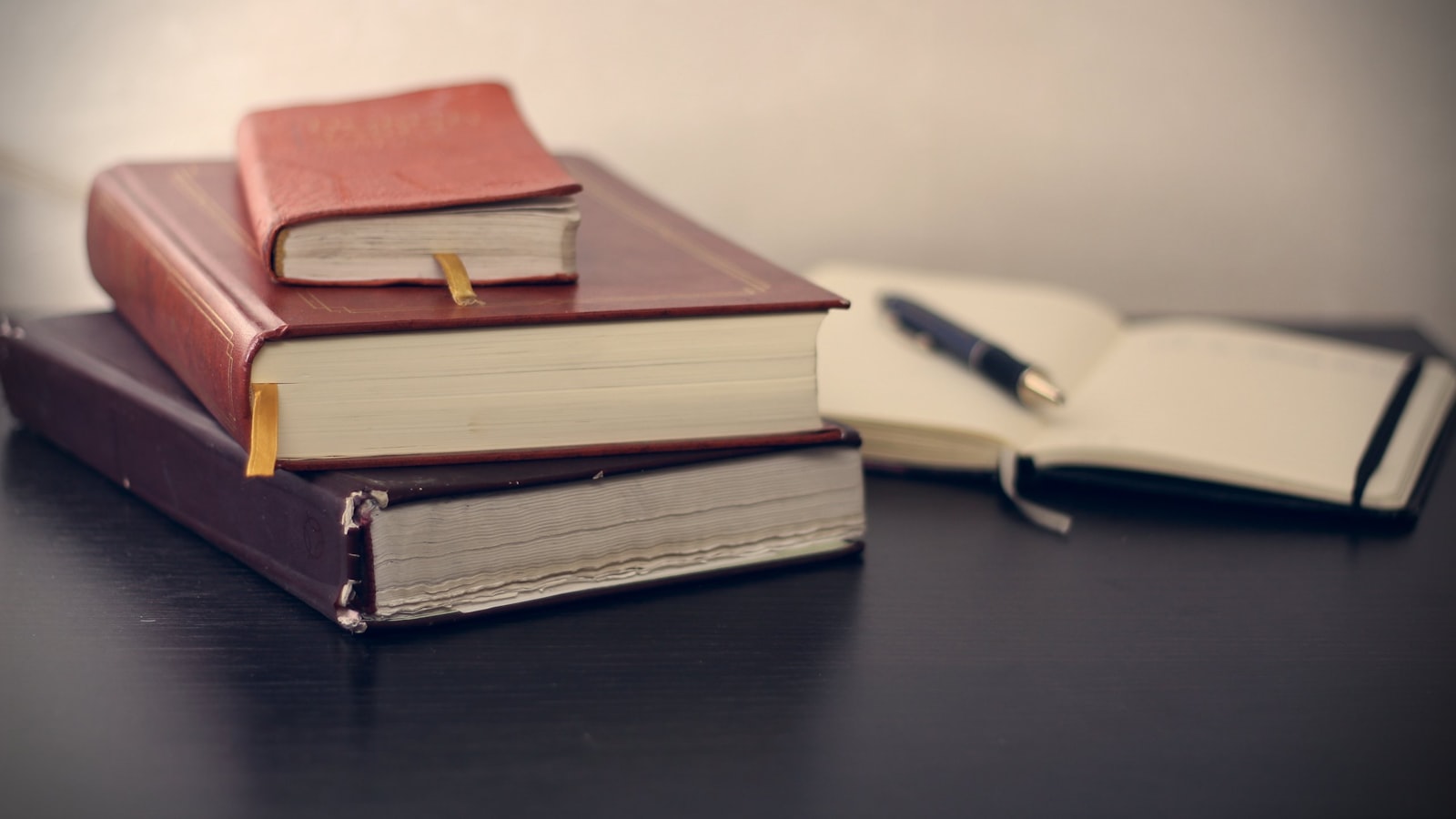 Códigos e livros de legislação tributária empilhados ao lado de caneta e caderno, base do trabalho consultivo