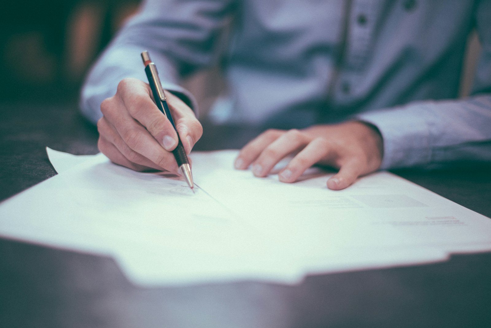Profissional assinando documento contratual com caneta, representando a formalização técnica e transparente do trabalho jurídico