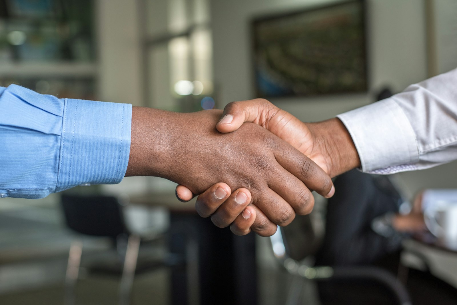 Aperto de mãos entre dois executivos em ambiente corporativo, simbolizando confiança e acordo profissional